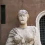 Madama Lucrezia stone bust with draped figure and coiled hair against a brick wall