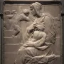 Madonna of the Stair stone relief showing a seated woman holding a child, with smaller figures on the stairs behind them.