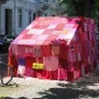 Ruhender Verkehr, a vehicle covered in a colorful knitted textile blanket on a city street.