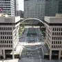The Ring, a large circular sculpture suspended above an urban plaza between two buildings.