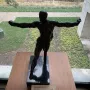 Standing Mercury, a dark bronze nude male sculpture posed with one leg lifted and both arms extended.