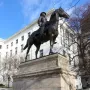 Equestrian statue of General Joseph Hooker in front of a classical building and iron fence.