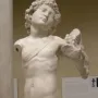 Marble Young Archer statue of a nude youthful male figure with curly hair, missing parts of its arms and legs.