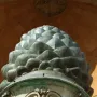 La Pigna sculpture resembling a giant green pine cone in front of a domed building