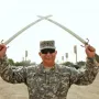 The Victory Arch with crossed swords towers in the background while a uniformed soldier stands in the foreground holding smaller swords.