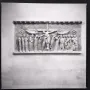 Marble relief from Descent from the Cross showing sorrowful robed figures beneath an inscription band, with a winged figure and a round medallion above.