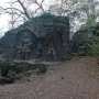Klácelka stone reliefs in a wooded setting, with carved figures in recessed niches and iron gates in front.