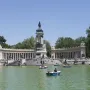 The Alfonso XII Monument with a central equestrian statue, flanked by curved colonnades beside a lake with rowboats.