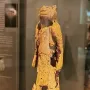 Fragmented Lion-man sculpture with an animal head and rough light-colored surface on a display base.