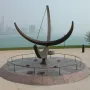 Man Enters the Cosmos sundial sculpture on a circular granite base with Chicago skyline and boats in the background.