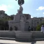 Fuente de la India marble fountain with a crowned female statue and fish sculptures at the base in a sunny plaza