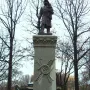 Firemen\'s Monument showing a bronze rescue worker holding a child and lantern atop a tall granite pillar.