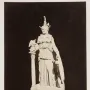 Varvakeion Athena shown in profile, holding a small winged figure beside a shield and column.