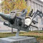 Humpty Dumpty sculpture with bronze mechanical forms, a golden disc marked \