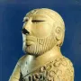 Bust of the Priest-King showing a bearded man in profile with carved facial hair and a patterned cloak.