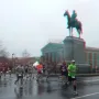 Robert E. Lee Monument with runners on a wet street in front of an equestrian statue on a tall stone base.