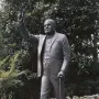 Winston Churchill statue holding a cane and raising a V sign outdoors.