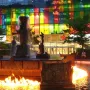 La Joute bronze fountain with water cascading from the center and flames burning on the surrounding pool.