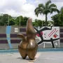 Cloud Shepherd, a bronze abstract sculpture with rounded forms and a central peak, stands in front of a geometric tiled wall.
