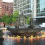 La Joute bronze fountain with water cascading from the center and flames burning on the surrounding pool.