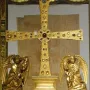 The Cross of the Angels, a jeweled golden cross displayed in a glass case with kneeling angel figures beside it.