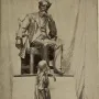 Dickens and Little Nell sculpture showing a seated bearded man and a standing girl looking up at him.