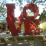 Bright red LOVE sculpture with a tilted O on a concrete base in Bustos, Bulacan.