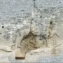 Madara Rider rock relief carved into a weathered cliff face, showing a mounted figure above a faint lion carving.