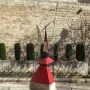 Nancy, a large abstract metal sculpture with red, black, and silver geometric forms on a stone pedestal in an outdoor courtyard.