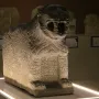 Stone lion sculpture with open mouth and carved symbols on its front