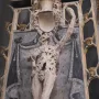 Transi of René of Chalon, an emaciated stone figure holding a heart to its chest in a dark niche.