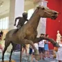 Jockey of Artemision bronze sculpture showing a young rider leaning forward on a horse in motion inside a museum.