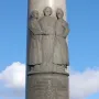 Electio Viritim Monument with a bronze relief of three figures on a tall light-grey column.