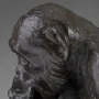 Bronze sculpture of a chimpanzee holding a human skull while seated on books, including one labeled Darwin.