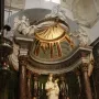 Crowned white marble Madonna di Trapani statue with the infant Jesus on an ornate altar with flowers and candles.