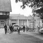 Crowds gather beside buildings on the plateau below the Kyffhäuser Monument, including a stone building and a modern café terrace.