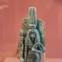 Ancient Egyptian statue of Queen Tiye with a tall headdress and patterned garment, holding a fan-like object.