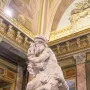 A marble sculpture of Aeneas, Anchises and Ascanius showing a man carrying an older man while a child clings to his leg.