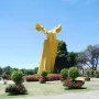 Ángel Custodio, a tall yellow abstract sculpture with curved wing-like shapes in a park.