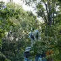 Major General John A. Logan equestrian statue on an ornate pedestal in a park, with a notice sign nearby.