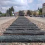 Monument to the Fallen and Murdered in the East stretching along a cobblestone median in Warsaw, with dark inscribed bars leading into a jagged structure.