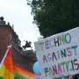 Tadeusz Kościuszko Monument seen as a dark silhouette atop a brick bastion above a colorful crowd and protest banners.