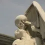 The Kiss of Death sculpture showing a skeletal figure leaning over a bare-chested man with its face pressed to his forehead.